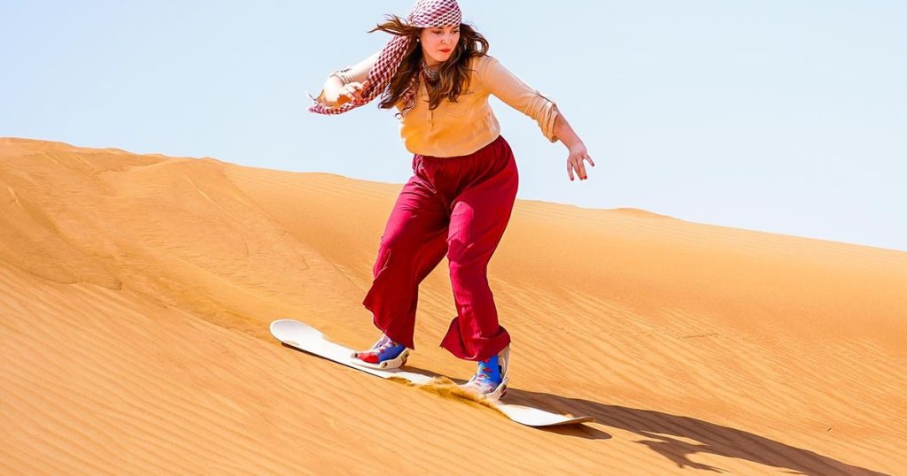 Teenagers sandboarding on Dubai desert dunes
