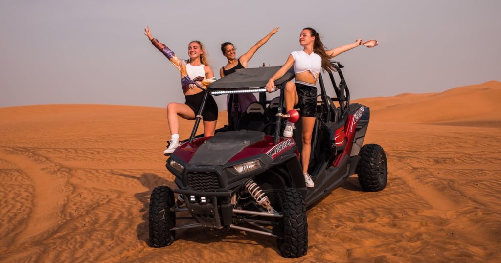 Teenagers riding dune buggies during Dubai desert safari